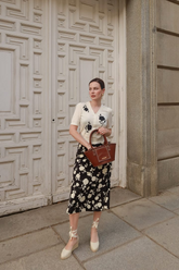 a lady in a white cardigan with rose embroidery and a white rose printed black skirt